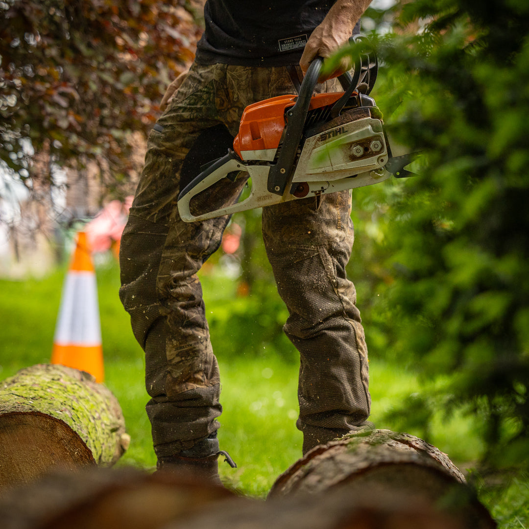 Person using a chainsaw on a log with a blurred background