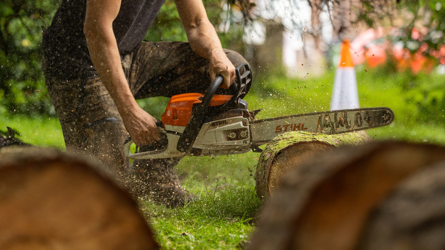 Person using a chainsaw to cut through wood in an outdoor setting
